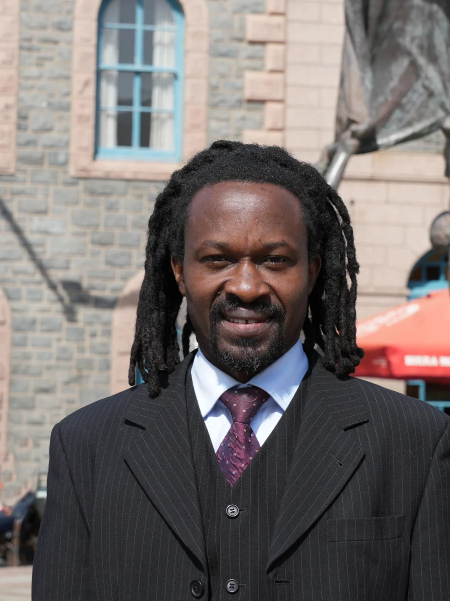 Martin Aliga, independent Senator candidate for Jersey 2026 election, photographed in St Helier with the Jersey flag and Liberation Square statue